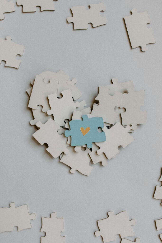 pexels-photo-8386118-8386118 A heart-shaped puzzle arrangement with a central blue piece featuring a gold heart symbol.